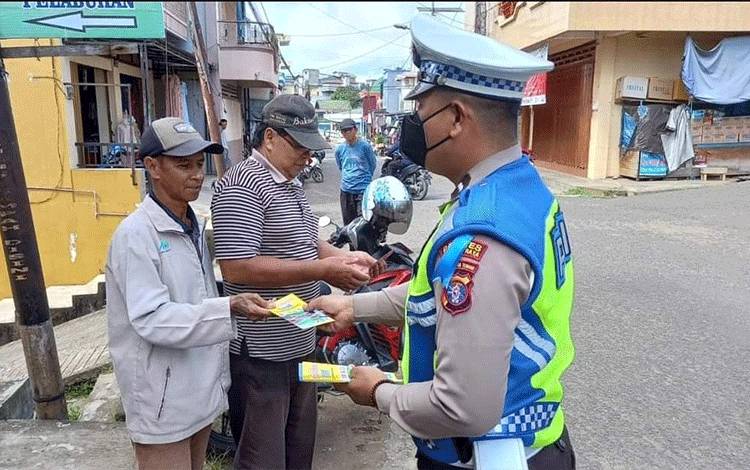 Personel Satlantas Polres Mura saat membagikan brosur tertib berlalu lintas kepada masyarakat.