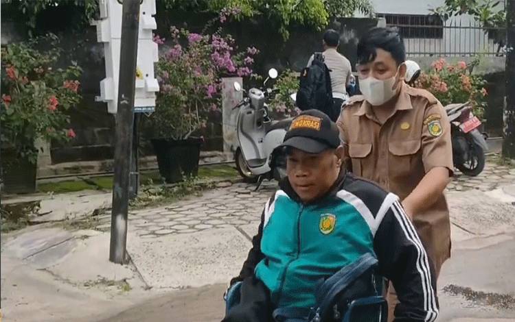 Pegawai di MPP Huma Betang Palangka Raya membantu disabilitas menaiki kursi roda. (FOTO: HENDRI)