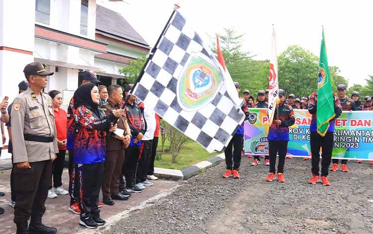 Wakil Bupati Seruyan, Hj Iswanti mengibarkan bendera tanda diberangkatkannya kontingen Seruyan mengikuti Porprov Kalteng di Sampit Kotim. (FOTO: IST)