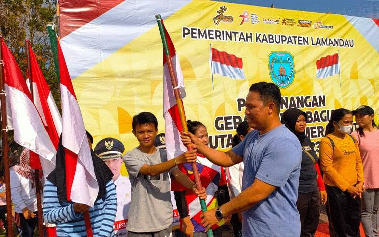 Bupati Lamandau Hendra Lesmana bagikan bendera merah putih kepada warga Nanga Bulik. (FOTO : HENDI NURFALAH)