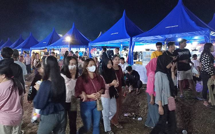 Pengunjung dengan latar stan UMKM meramaikan malam pembukaan Bartim Expo 2023, Selasa, 8 Agustus 2023. (FOTO: BOLE MALO)