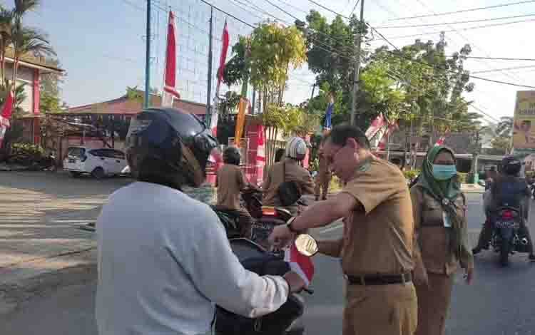 Jajaran BPPRD Kapuas saat bagikan bendera kepada pengendara melintas di Jalan Tambun Bungai. (FOTO: IST)