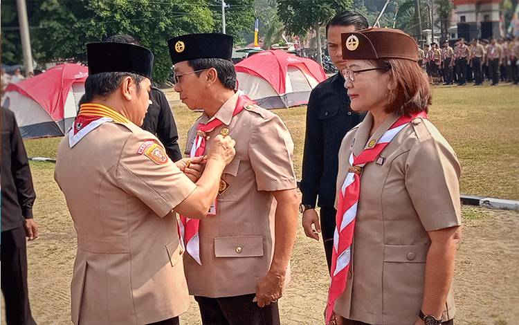 Bupati Barito Timur Ampera AY Mebas menyempatkan lencana kepada Sekretaris Daerah Panahan Moetar pada upacara peringatan Hari Pramuka ke-62, Kamis, 31 Agustus 2023. (FOTO: BOLE MALO)
