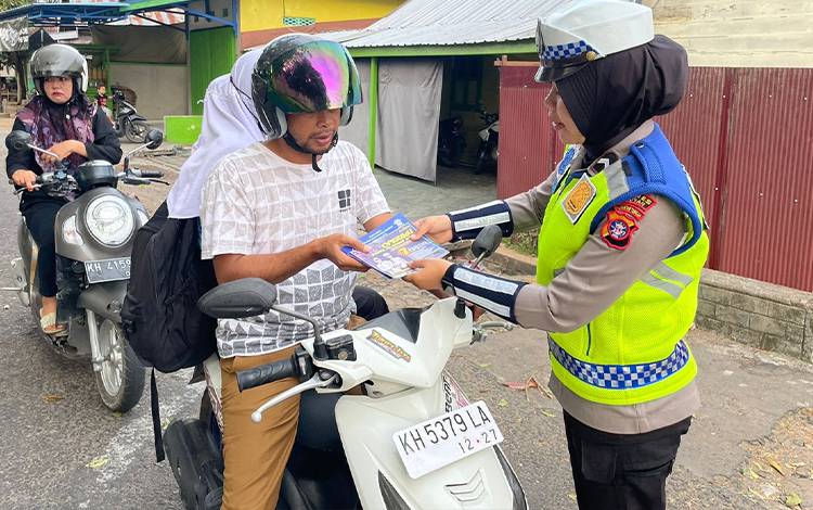 Personel Satlantas Polres Seruyan membagikan stiker dan buku panduan kepada pengendara di Kuala Pembuang. (FOTO: IST)