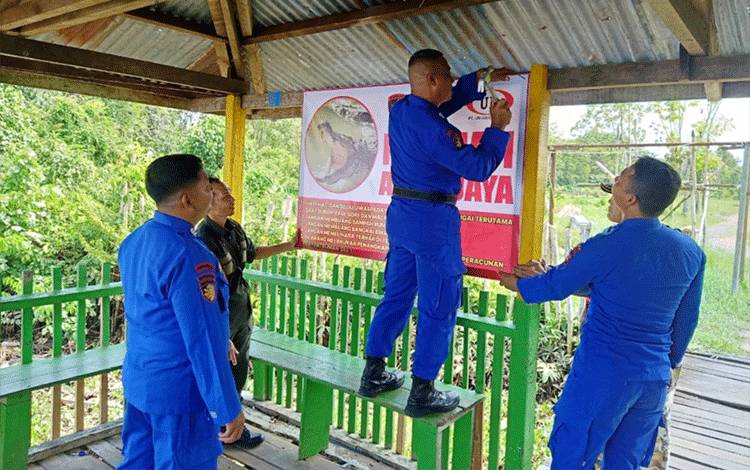 Anggota Ditpolairud Polda Kalteng saat memasang papan peringatan kemunculan buaya di sekitar Sungai Mentaya Sampit. (FOTO: IST)