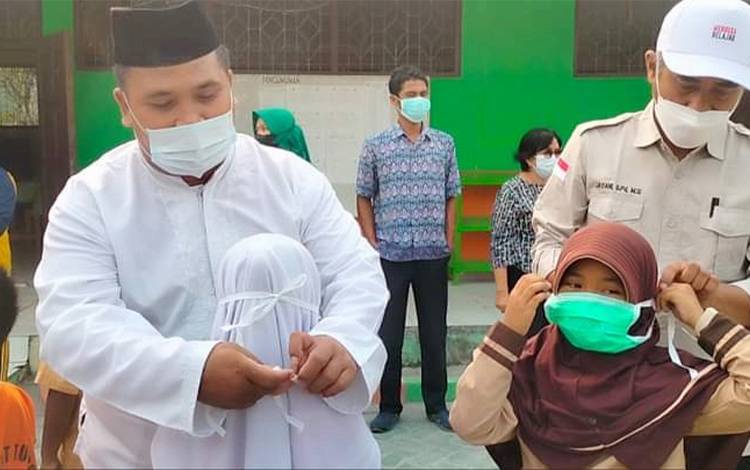 Masker dipasangkan kepada siswa SDN 3 Petuk Katimpun dalam kunjungan Kadisdik pada Jumat, 29 September 2023. (FOTO: Protokol Komunikasi Kota Palangka Raya)