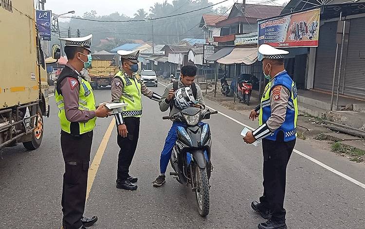 Petugas Satlantas Polres Barito Timur saat membagikan masker gratis kepada pengguna jalan di depan Pasar Tamiang Layang, Selasa, 3 Oktober 2023. (FOTO: IST)