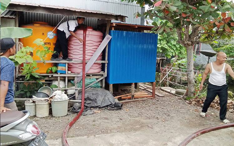Petugas Perumda Tirta Barito menyalurkan air bersih menggunakan tangki. (FOTO :URIUTU DJAPER)