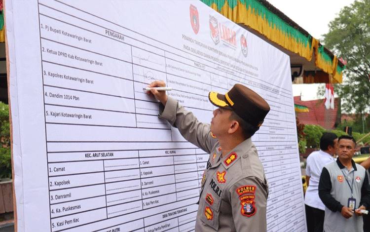 Kapolres Kobar AKBP Bayu Wicaksono saat bubuhkan tanda tangan di papan deklarasi Pilkades Damai. (Foto : ISTIMEWA)