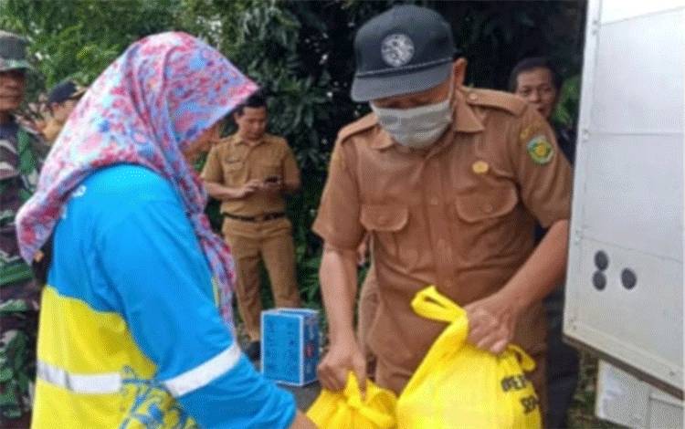 Staff Disperindagkop Kota Palangka Raya saat menyerahkan sembako dalam kegiatan operasi pasar di Kelurahan Tumbang Rungan (Foto : Disperindagkop Kota Palangka Raya)