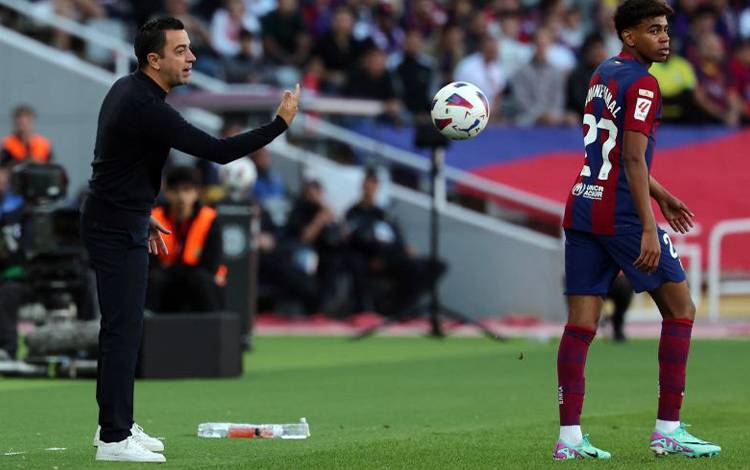 Pelatih Barcelona Xavi Hernandes melempa bola pada pemainnya, Lamine Yamal, dalam pertandingan Barcelona vs Real Madrid di Barcelona, Spanyol, Sabtu. (ANTARA/AFP-LLUIS GENE)