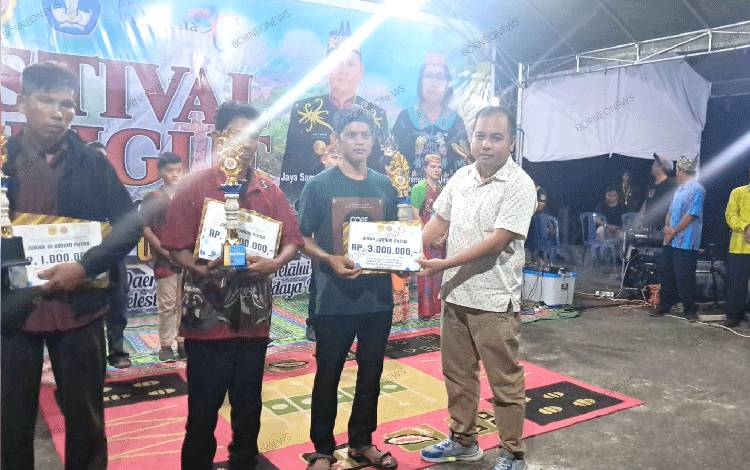 Anggota DPRD Gunung Mas Evandi saat menyerahkan hadiah kepada pemenang Festival Karungut, Senin, 13 November 2023 malam. (FOTO: RISKA YULYANA)
