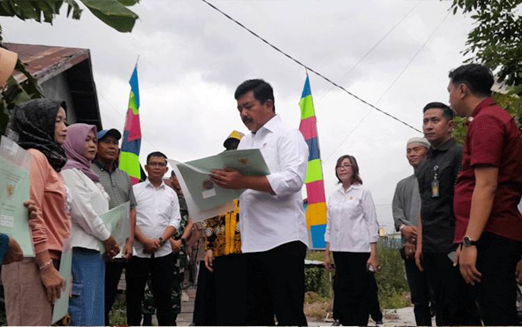  Menteri ATR/BPN Hadi Tjahjanto saat menyerahkan sertifikat tanah kepada warga di Kelurahan Bukit Tunggal,Kecamatan Jekan Raya, Kota Palangkaraya, Kamis, 16 November 2023. (Foto: MARINI)
