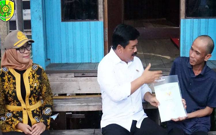 Pj Wali Kota Palangka Raya, Hera Nugrahayu mendampingi Menteri ATR/BPN menyerahkan sertifikat tanah. (FOTO: HUMAS)