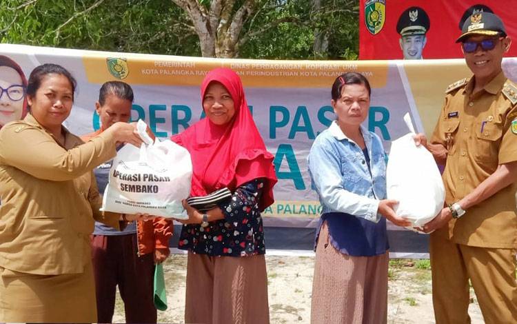Anggota DPKUKMP Palangka Raya saat menyerahkan paket sembako pada operasi pasar di Kelurahan Tangkiling (Foto : DPKUKMP Palangka Raya)