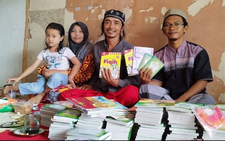 Hakam saat membagi buku Iqro dan buku cerita anak-anak ke tempat belajar mengaji di Sampit yanhdiasuh Ustaz Abdul Khair. Tampak dari kiri: anak dan istri Hakam, serta Ustaz Abdul Khair (paling kanan).