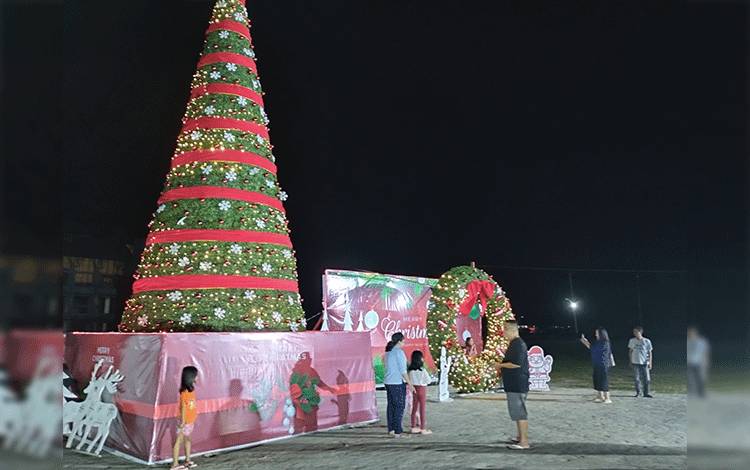 Masyarakat Kota Cantik antusias mengambil gambar di depan pohon natal raksasa dan dekorasi ukuran besar yang tersedia di halaman GOR Serbaguna Indoor Km 5, Minggu malam, 3 Desember 2023. (FOTO: TESTI PRISCILLA)