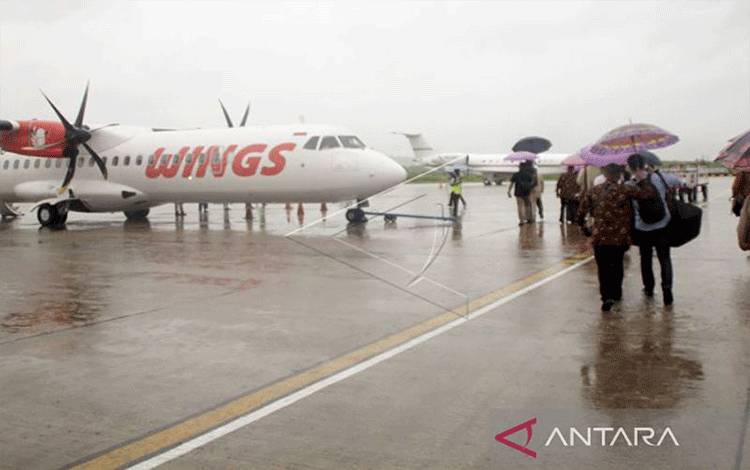 Sejumlah penumpang pesawat menggunakan payung menuju pesawat di bandara El Tari Kupang.ANTARA/Kornelis Kaha