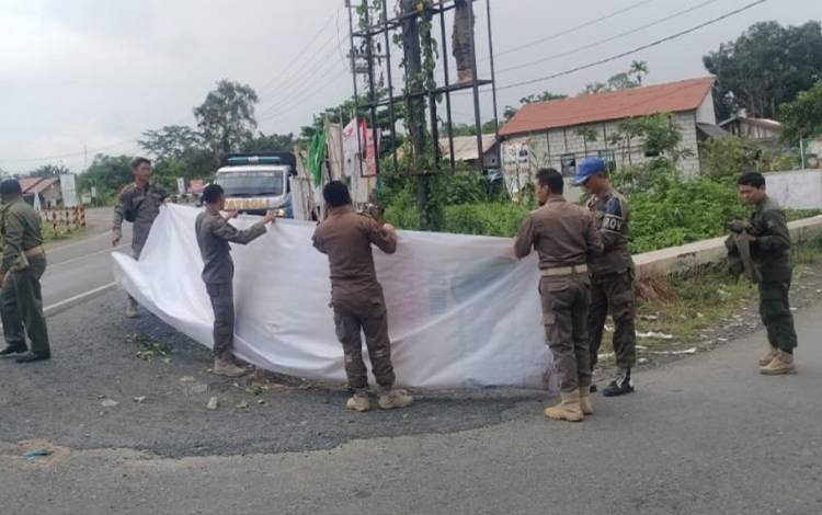 Personel Satpol PP dan Damkar Kapuas saat lakukan penertiban spanduk di pinggir Jalan Lintas Kalimantan. (FOTO: IST)