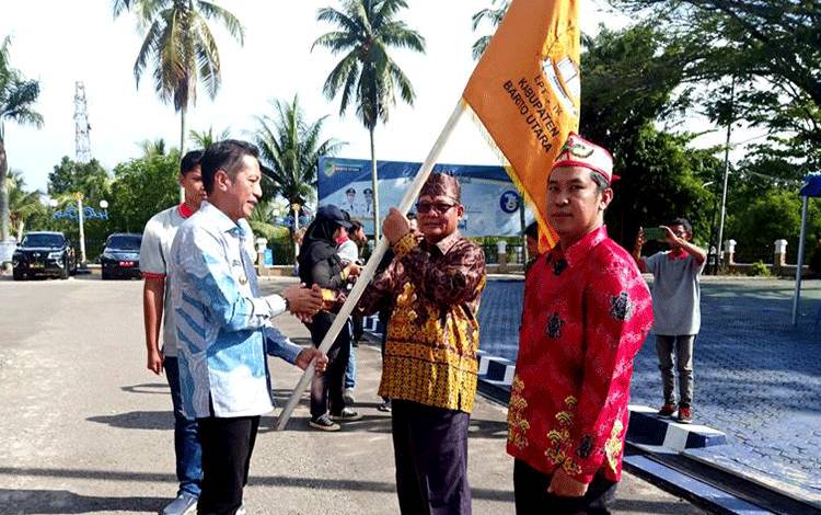 Pj Bupati Barito Utara Drs Muhlis menyerahkan bendera lambang daerah kepada ketua LPTIK Barito Utara Ardiano usai pelepasan di halaman kantor Bupati, Sabtu 16 Desember 2023.(foto: Dhani)