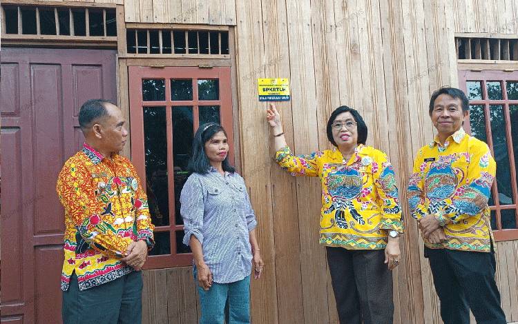Wakil Bupati Gunung Mas Efrensia L.P Umbing saat menempel tanda di rumah penerima program BPKRTLH. (FOTO: RISKA YULAYANA)