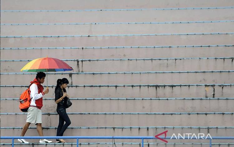 Arsip Foto - Dua remaja menggunakan payung guna melindungi diri dari hujan di kawasan Senayan, Jakarta. (ANTARA/ANDIKA WAHYU)