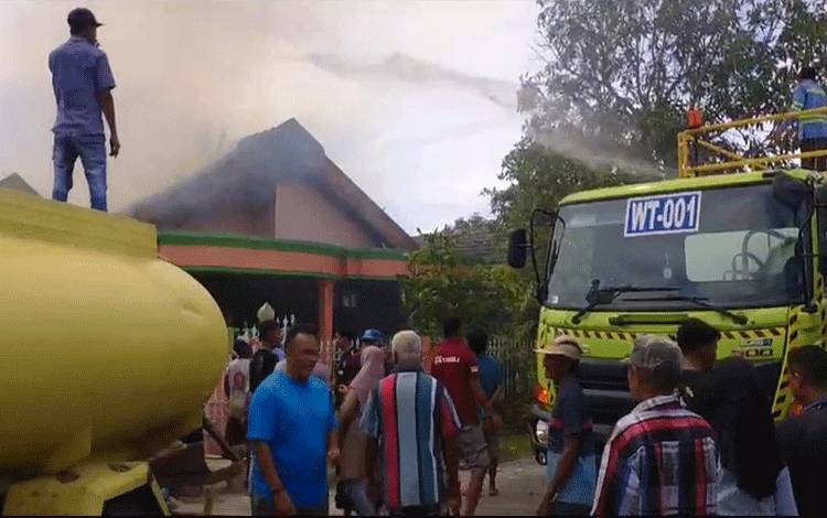 Petugas bersama warga berupaya memadamkan api yang membakar rumah di Rt 4 Desa Kubu, Kecamatan Kumai, pada Minggu, 31 Desember 2023. (Foto : Tangkapan Layar)