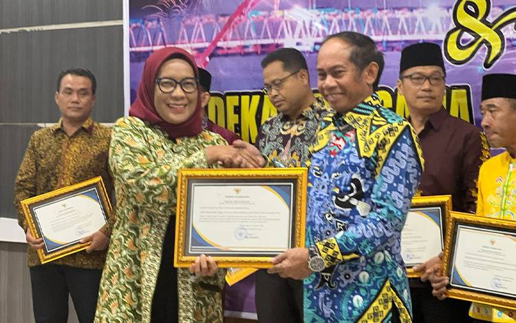 Pj Wali Kota Palangka Raya, Hera Nugrahayu memberikan piagam penghargaan kepada kepala DPMPTSP. (FOTO: HUMAS)