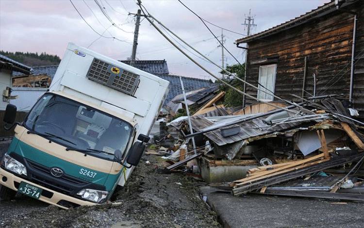 Puing-puing berserakan dan kendaran amblas masuk jalan yang rusak akibat gempa terlihat di Kota Wajima, Prefektut Ishikawa, Jepang, pada 5 Januari 2024. (Kyodo)