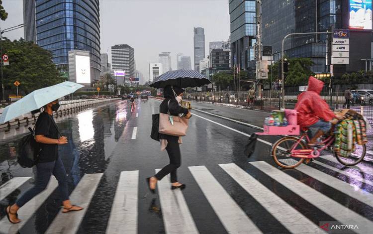 Sejumlah warga menggunakan payung saat hujan di kawasan Jalan Jenderal Sudirman, Jakarta, Selasa (4/10/2022). Badan Meteorologi Klimatologi dan Geofisika (BMKG) menyatakan potensi curah hujan dengan intensitas sedang hingga lebat yang dapat disertai kilat atau petir dan angin kencang untuk periode tanggal 2-8 Oktober 2022 di wilayah DKI Jakarta dengan status waspada. ANTARA FOTO/M Risyal Hidayat/tom. (ANTARA FOTO/M RISYAL HIDAYAT)