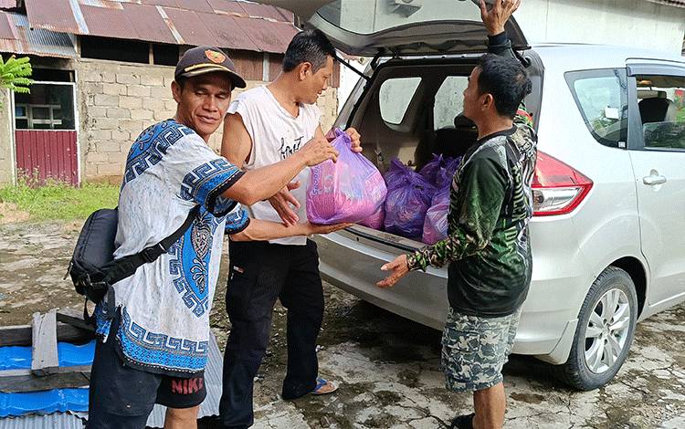 Kepala Desa Jaar Sugiyanto (tengah), bersama perangkat desa sedang menaikkan paket bantuan bahan kebutuhan pokok ke mobil sebelum didistribusikan ke warga terdampak banjir, Sabtu, 13 Januari 2023. (FOTO: BOLE MALO)