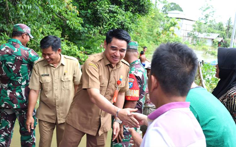 Kepala Pelaksana BPBD Barito Utara, Simamoraturahman bersama instansi terkait saat menyerahkan bantuan logistik bagi korban banjir. (FOTO: DHANI)