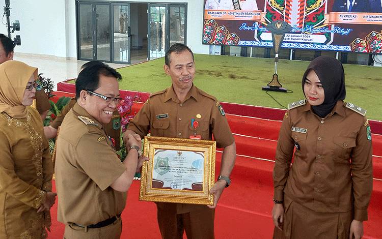 Pj Bupati Kapuas, Erlin Hardi saat berikan piagam penghargaan kepada Kepala Dinas PUPRPKP Teras, bertempat di Aula Rujab Bupati. (FOTO: IST)