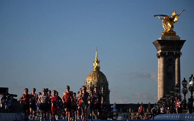Para atlet berlari pada estafet campuran format Triatlon Duathlon Dunia 2023 dalam tes event Olimpiade di jembatan Alexandre III dengan latar belakang Hotel des Invalides di Paris, pada 20 Agustus 2023. (AFP/EMMANUEL DUNAND)
