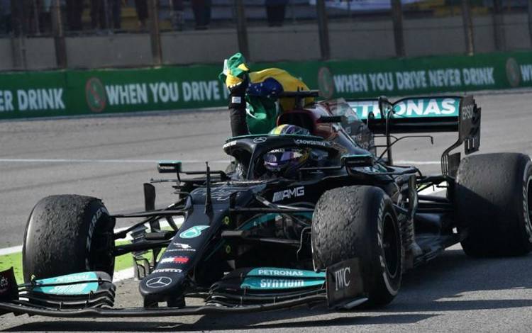Foto arsip - Pebalap Mercedes Lewis Hamilton melakukan selebrasi dengan mengibarkan bendera Brasil setelah memenangi Grand Prix Sao Paulo, Autodromo Jose Carlos Pace, Interlagos. (14/11/2021) (AFP/NELSON ALMEIDA)