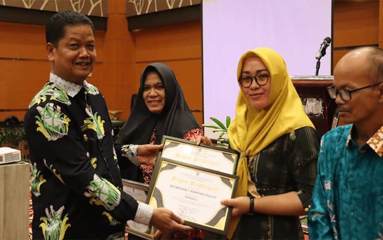 Pj Bupati Seruyan Djainuddin Noor menyerahkan Piagam Penghargaan dari Dinas Pendidikan kepada sekolah yang berhasil mengelola asset sekolah terbaik (FOTO : PROKOM SERUYAN)