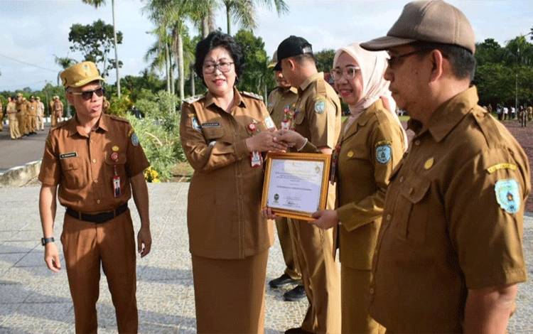 Penjabat Bupati Lamandau Lilis Suriani memberikan penghargaan kepada salah satu ASN berprestasi. (FOTO : HENDI NURFALAH)