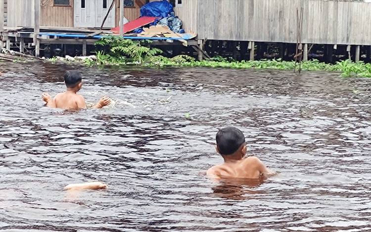 Anak-anak bermain saat banjir di Kota Palangka Raya. Dinkes Kalteng mengingatkan ada beberapa penyakit rawan menjangkit saat banjir. (FOTO: HERMAWAN)