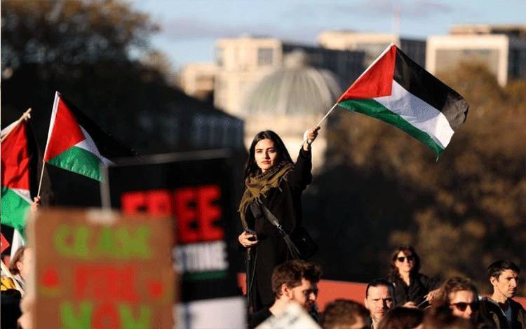 Seorang wanita di tengah kerumunan massa mengibarkan bendera Palestina. Ratusan ribu warga Inggris turun ke jalan dalam unjuk rasa di London Inggris itu pada Sabtu (11/11/2023) dan menyerukan gencatan senjata segera dilakukan di Jalur Gaza. (ANTARA/Xinhua/Li Ying)