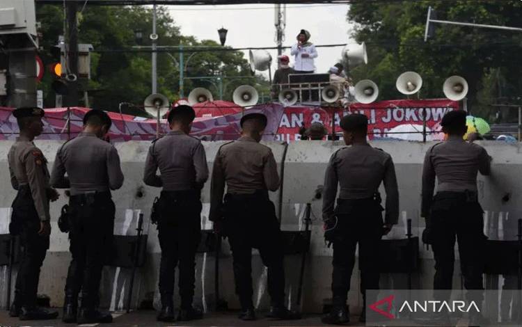 Polisi mengawasi aksi demonstrasi dari balik barikade di depan Gedung KPU, Jakarta, Senin (18/3/2024). ANTARA FOTO/Indrianto Eko Suwarso