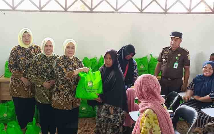 Ketua Ikatan Adhyaksa Dharmakarini (IAD) Kalimantan Tengah Dessy Undang Mugopal, saat menyerahkan secara simbolis paket sembako kepada salah satu warga. (FOTO: FAHRUL)