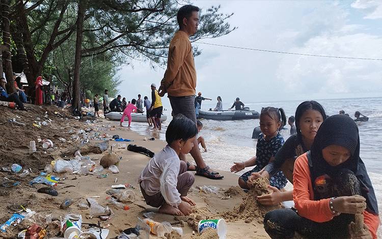 Anak-anak bermain pasir di antara sampah plastik di Pantai Ujung Pandaran, Sabtu, 13 April 2024.