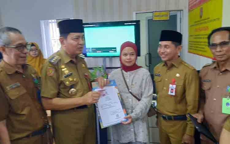 Pj Bupati Kobar Budi Santosa saat menyerahkan dokumen hasil pelayanan di MPP. (FOTO: DANANG)
