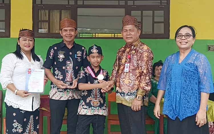 Evan Dhytra didampingi kedua orang tua dan Kepala SD Negeri 4 Tamiang Layang menerima ucapan selamat dari Kepala Dinas Pendidikan Kabupaten Barito Timur, Sabai. (FOTO: IST)
