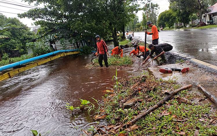 Petugas membersihkan sumbatan di gorong-gorong Sungai Mentawa, Jalan HM Arsyad, Senin, 29 April 2024. (DEWI PATMALASARI)