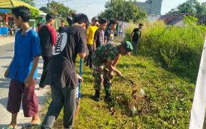 Babinsa Bersama Warga Gotong Royong Bersihkan Rumput Liar di Parit